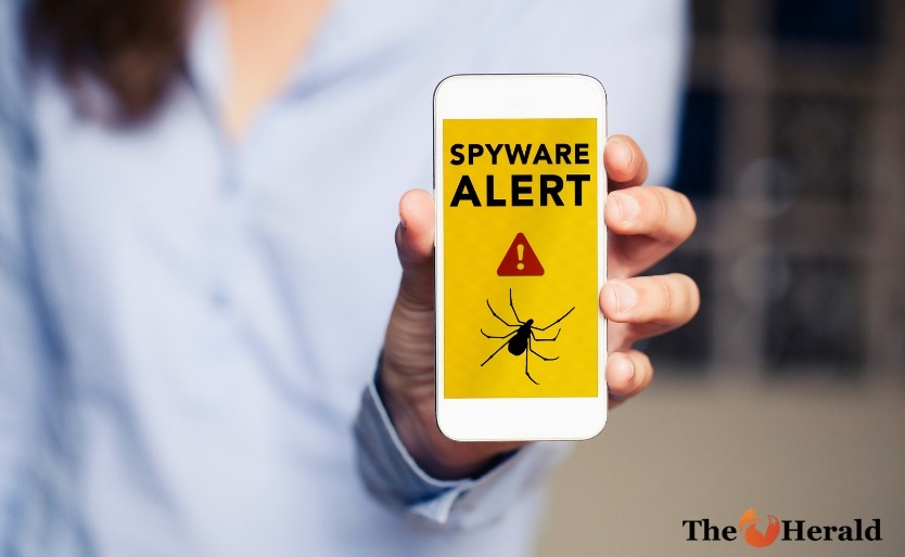 Spyware alert in a mobile phone held by hand.