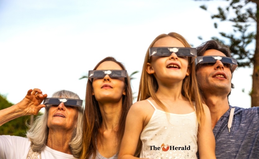 Famille regardant l’éclipse solaire utilisant des verres solaires